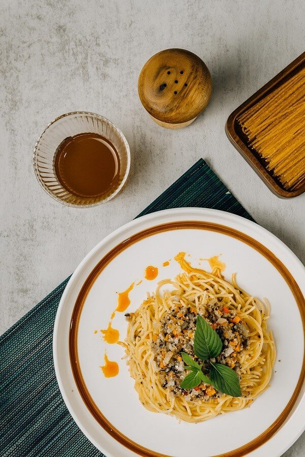 Növényi élelmiszer pl. a tojásmentes spagetti olajokkal, zöldfűszerekkel, magvakkal és zöldségekkel